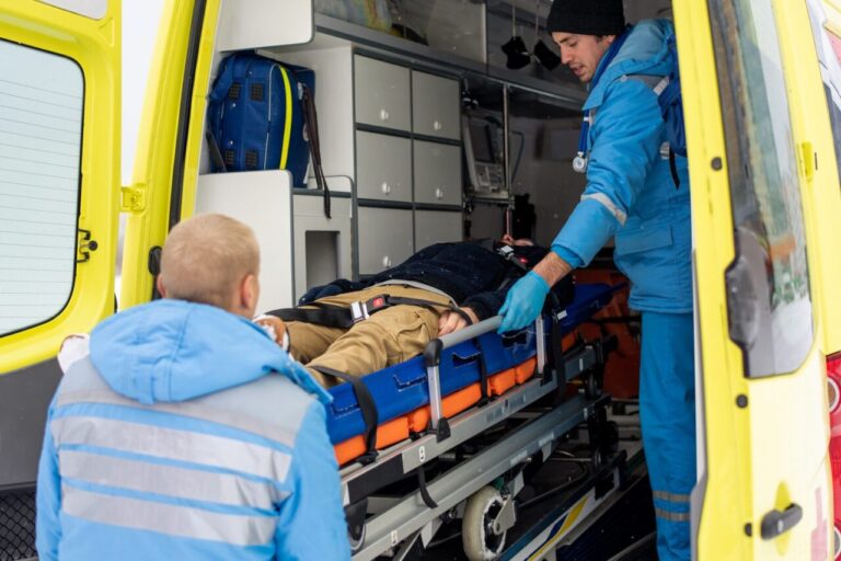 Un ambulancier installe un patient sur un brancard avant un transport médicalisé.