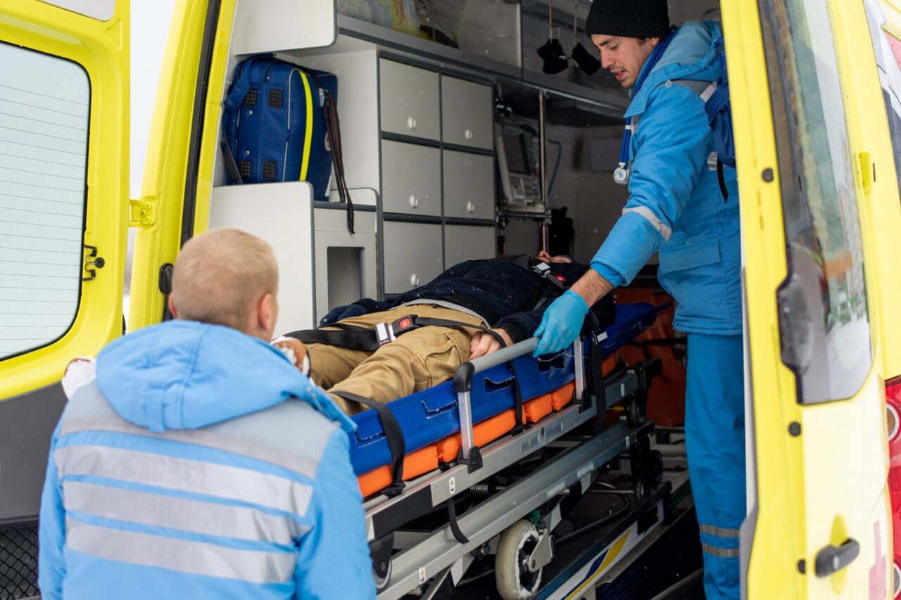 Un ambulancier installe un patient sur un brancard avant un transport médicalisé.
